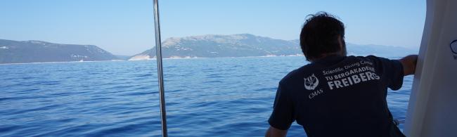 Instructor for scientific diving on a boat with a view into the distance