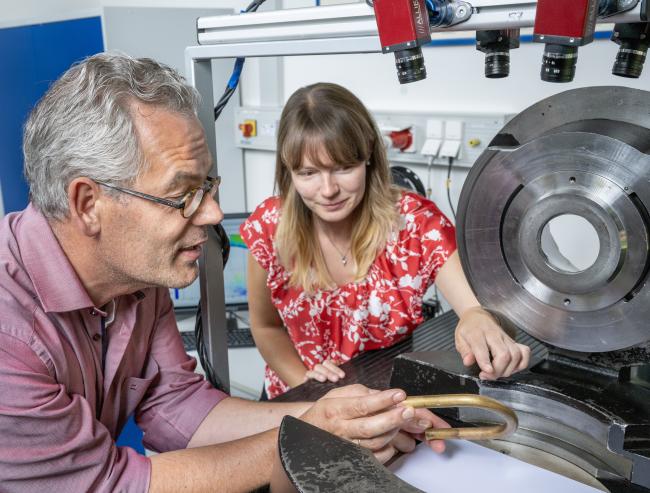 Susanne Berndorf und Prof. Ulrich Prahl prüfen ein Werkstück eines Blechblasinstruments.