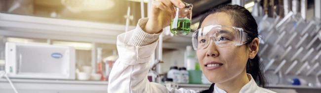 Eine Nachwuchswissenschaftlerin in einem Chemielabor untersucht eine Probe