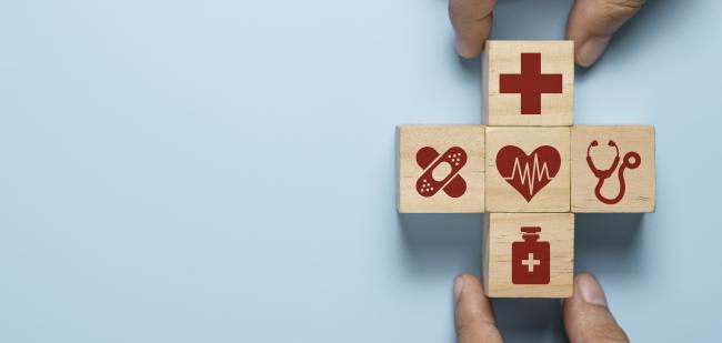 Holzwürfel mit den Symbolen Rotes Kreuz, Pflaster, Herzrhythmus, Stetoskop und Medizinfläschchen