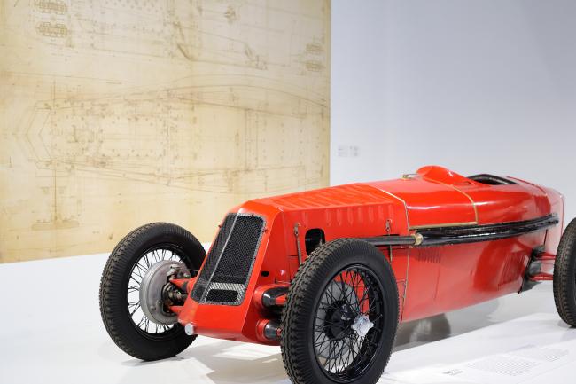 Ein Roter Oldtimer vor seinem Bauplan im Maßstab 1:1 im Turiner Nationalen Automobilmuseum Italien