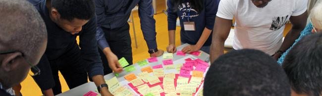 Gruppe von Menschen, die um einen Tisch stehen und planen.