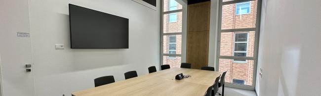 Gruppenarbeitsraum mit Tischen, Stühlen und Monitor an der Wand