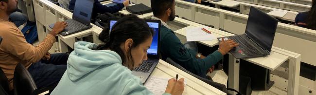 Blick in einen Hörsaal, Studierende arbeiten an Laptops