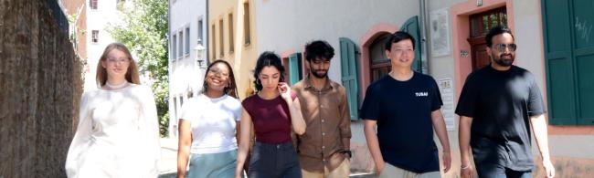 Drei weibliche und drei männliche internationale Studierende laufen eine Gasse in Freibergs Altstadt entlang