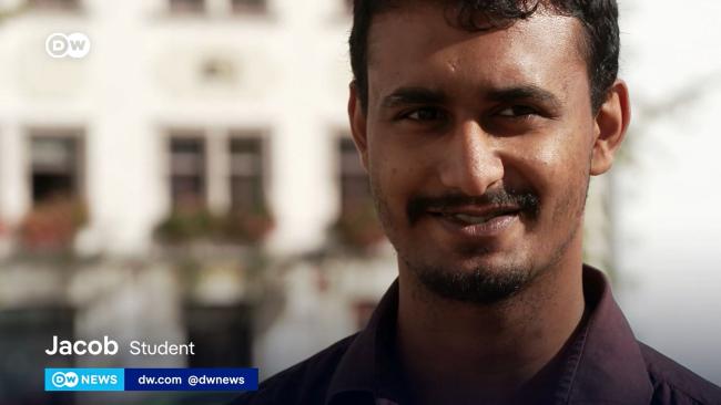 Bildschirmfoto eines Fernsehbeitrages: Nahaufnahme eines Studenten mit Texteinblendungen: Jacob Student. DW News. dw.com @dwnews