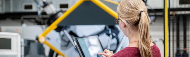 Eine Studentin steht vor einer modernen Werkzeugmaschine