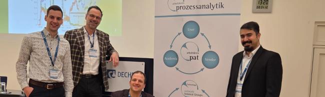 Personen stehen im Dechema Haus vor dem PAT Aufsteller