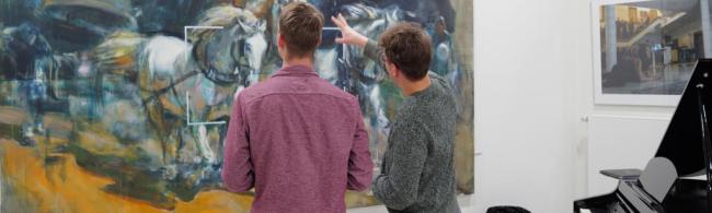 Zwei Männer betrachten ein Bild.