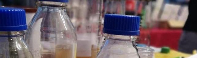 Fläschen mit körnigem Inhalt, im Hintergrund leere Biergläser