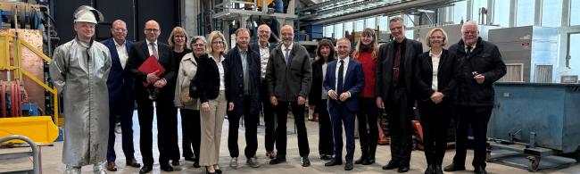 Eine Menschengruppe steht in einer Gießerei-Halle