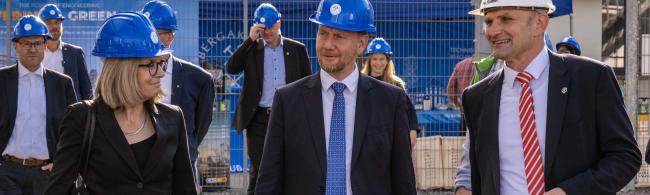 Drei Personen in Anzügen und mit Helmen
