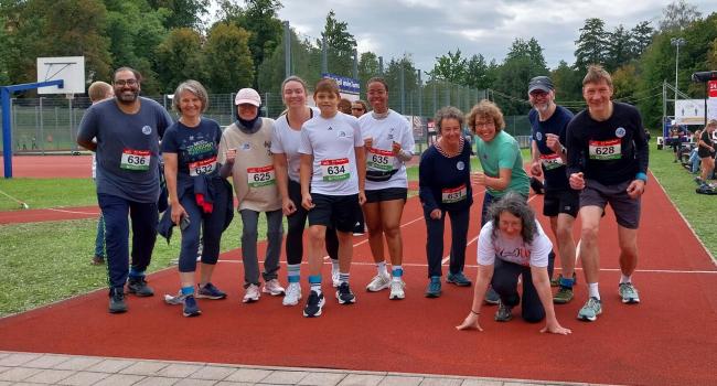 Sportlerinnen und Sportler posieren auf einer roten Tartanbahn für ein Gruppenfoto