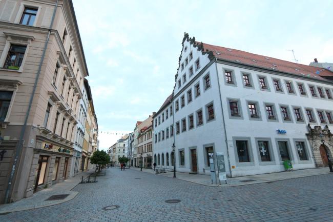 Eine Fußgängerzone in einer Altstadt mit einem weißen Bürgerhaus im Fordergrund