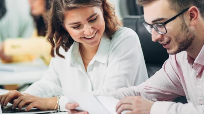 zwei Studierende sitzen an einem Laptop