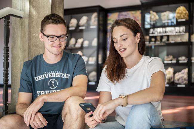 Zwei Studierende unterhalten sich auf einer Treppe