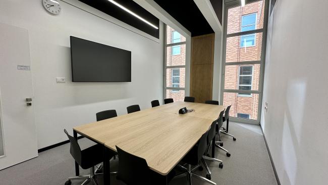 Group study room with tables, chairs and monitor on the wall