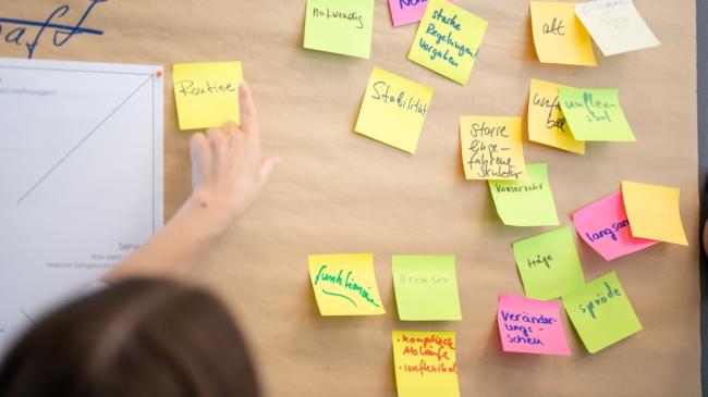 Post-its werden an eine Tafel geklebt.