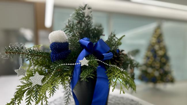 Bild zeigt einen Weihnachtsgesteck mit einer blauen Schleife und silbernen Sternen