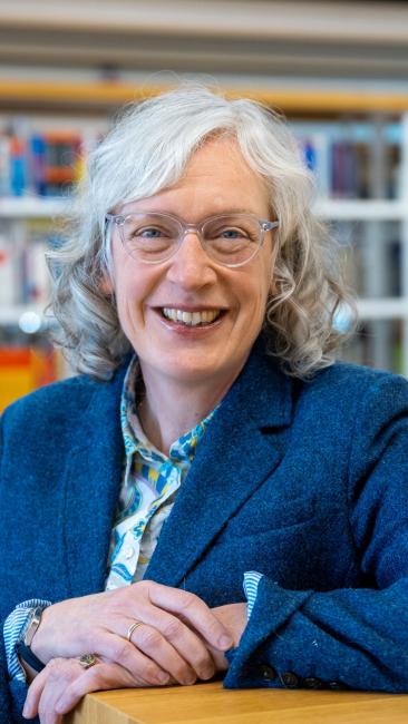 Lächelnde Frau vor einer Bücherwand 