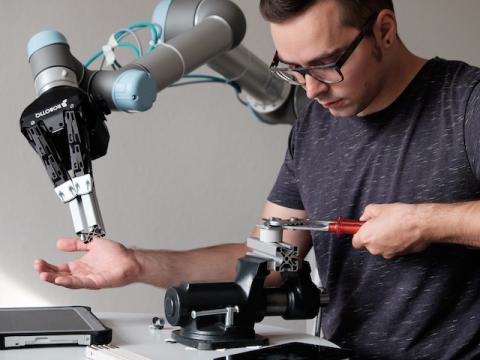 Robotischer Assistent übergibt ein Bauteil an Monteur