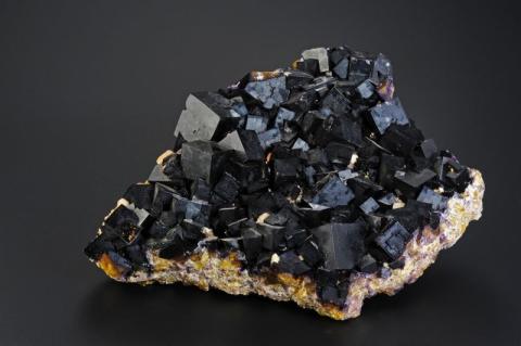 Ein Mineral mit glänzend schwarzen Kristallen auf hellem Grund