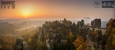 Foto der Bastei im Sonnenaufgang mit Logos der GADEST-Konferenz, TUBAF, IAP.