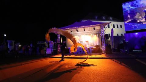 Das Drachenband zeichnet dekorative Kreisformen im orangenen Gegenlicht der Bühnenbeleuchtung