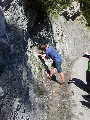 Studierender untersucht mit Schmidthammer die Gesteinsfestigkeit