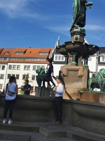 Dr. Martin Dirauf reitet auf einem der vier Löwen am Brunnen am Obermarkt in Freiberg