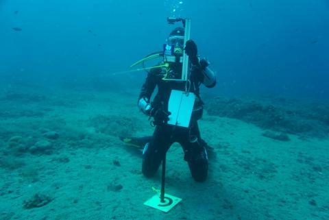 Taucher während der Benutzung eines Lagebestimmungsmessgerätes mittels Laser
