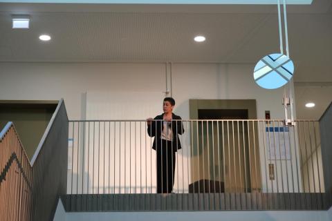 Eine Frau steht am Treppengeländer.