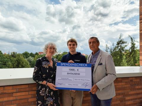 Drei Personen halten einen Spendencheck.