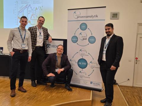 Personen stehen im Dechema Haus vor dem PAT Aufsteller