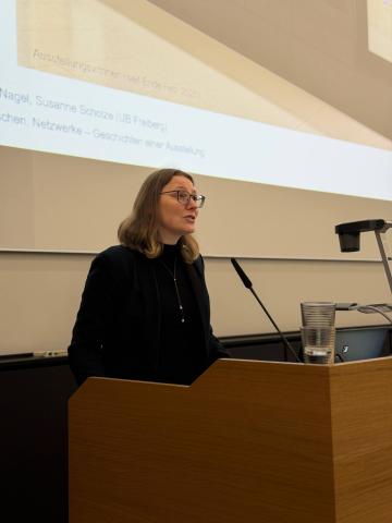 Eine Person stehen an einem Pult und hält Vortrag.