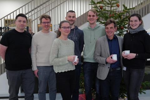 Sieben Personen stehen vor einem Weihnachtsbaum.