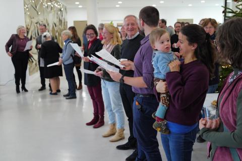 Stehendes Publikum mit Liedtexten in der Hand.