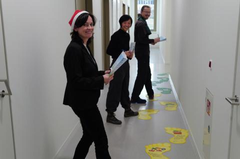 Drei Personen spielen ein Spiel mit großen Fußaufklebern  auf dem Boden.