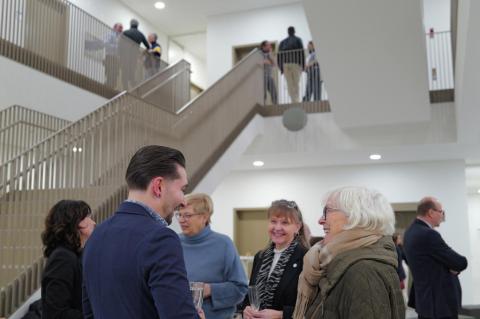Personen unterhalten sich vor Treppe.