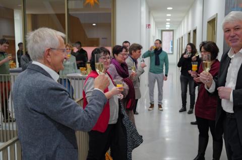 Personen stehen mit Gläsern in der Hand im Treppenhaus.