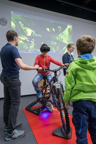Ein Kind mit VR-Brille auf einem Fahrrad