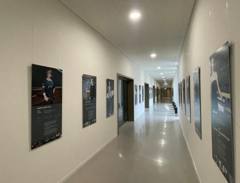 Blick in ein einen langen Gang, der mit Fotografien an den Wänden geschmückt ist.