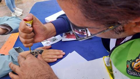 Ein Mann verziert die Hand eines Kindes mit Henna. Dafür nutzt er eine Schablone, die einen Stern zeigt.