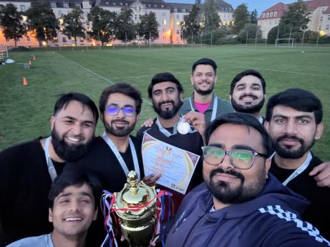 Ein Cricket-Team aus acht Spielern mit einem Pokal und einer Urkunde