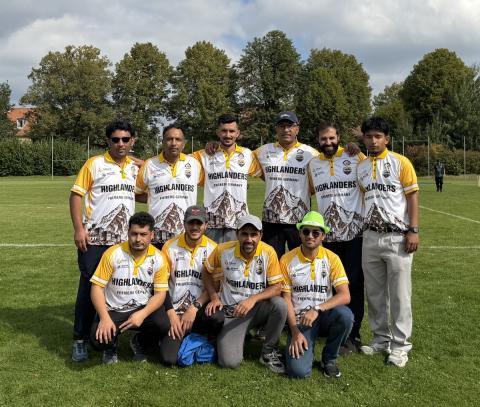 Eine Cricketmannschaft in gelb-weißen Dressen posiert auf einem Rasensportplatz