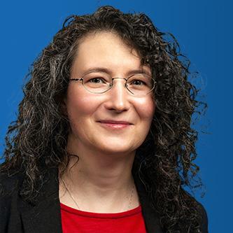 Portraitfoto einer Frau mit Brille vor marineblauem Hintergrund