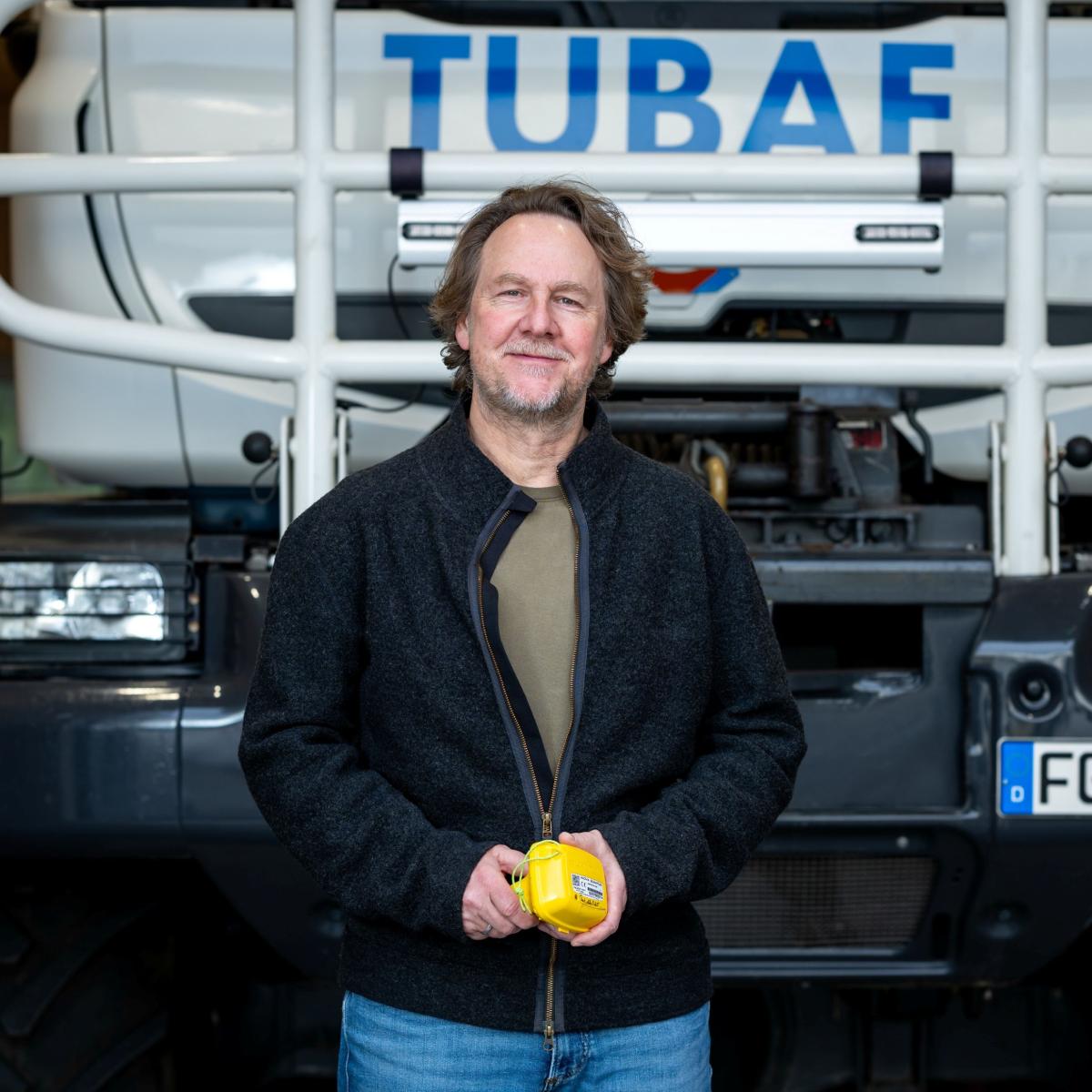 Ein Mann steht vor der Rückseite eines Spezial-LKWs mit der Aufschrift "TUBAF"