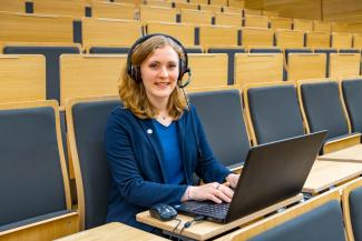 Eine junge Frau mit Laptop und Headset im Hörsaal