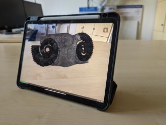 Im Tablet ist sieht man zwei Ammoniten die mittel Augmented Reality auf einen Tisch projiziert werden