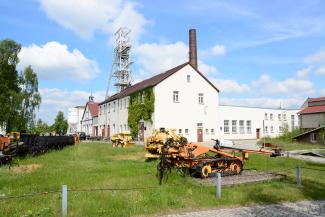 Bergwerksgebäude der Reichen Zeche mit historischen Maschinen im Vordergrund